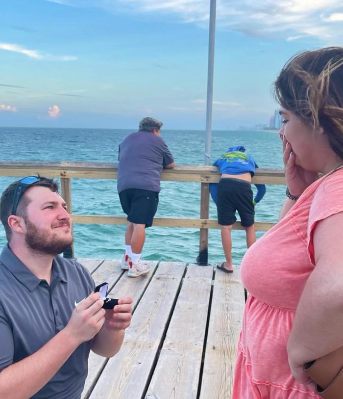 Proposed to my girlfriend yesterday and just noticed the guy in the back is not having a good time 😂