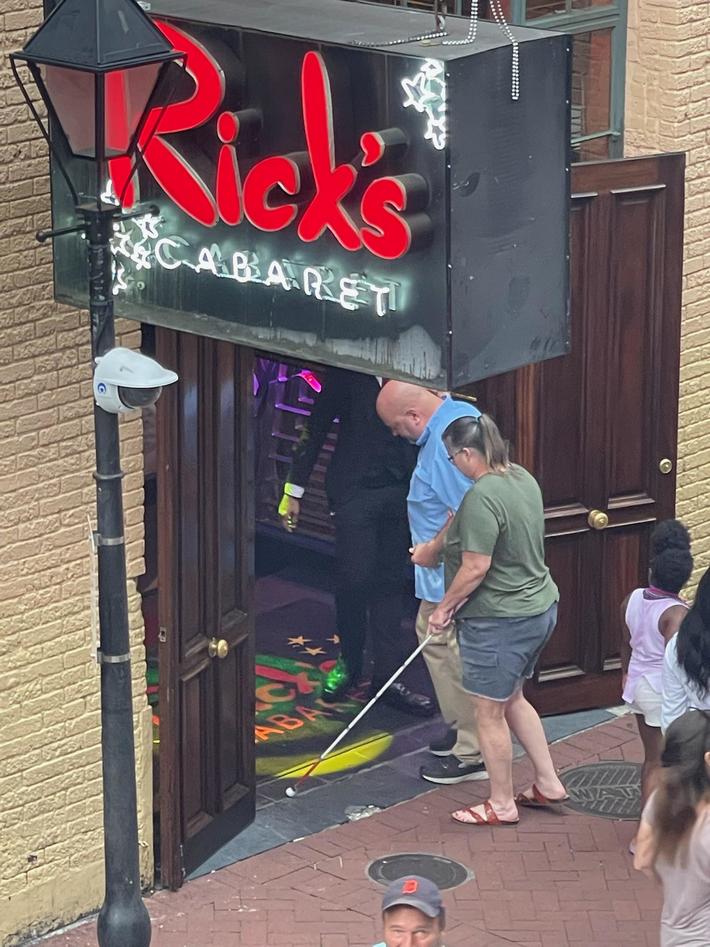 Husband leading blind wife into strip club