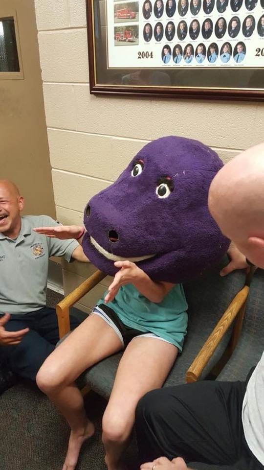 A girl at the fire station after getting stuck in a Barney head